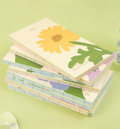 Stack of colorful greeting cards with floral designs on a green background