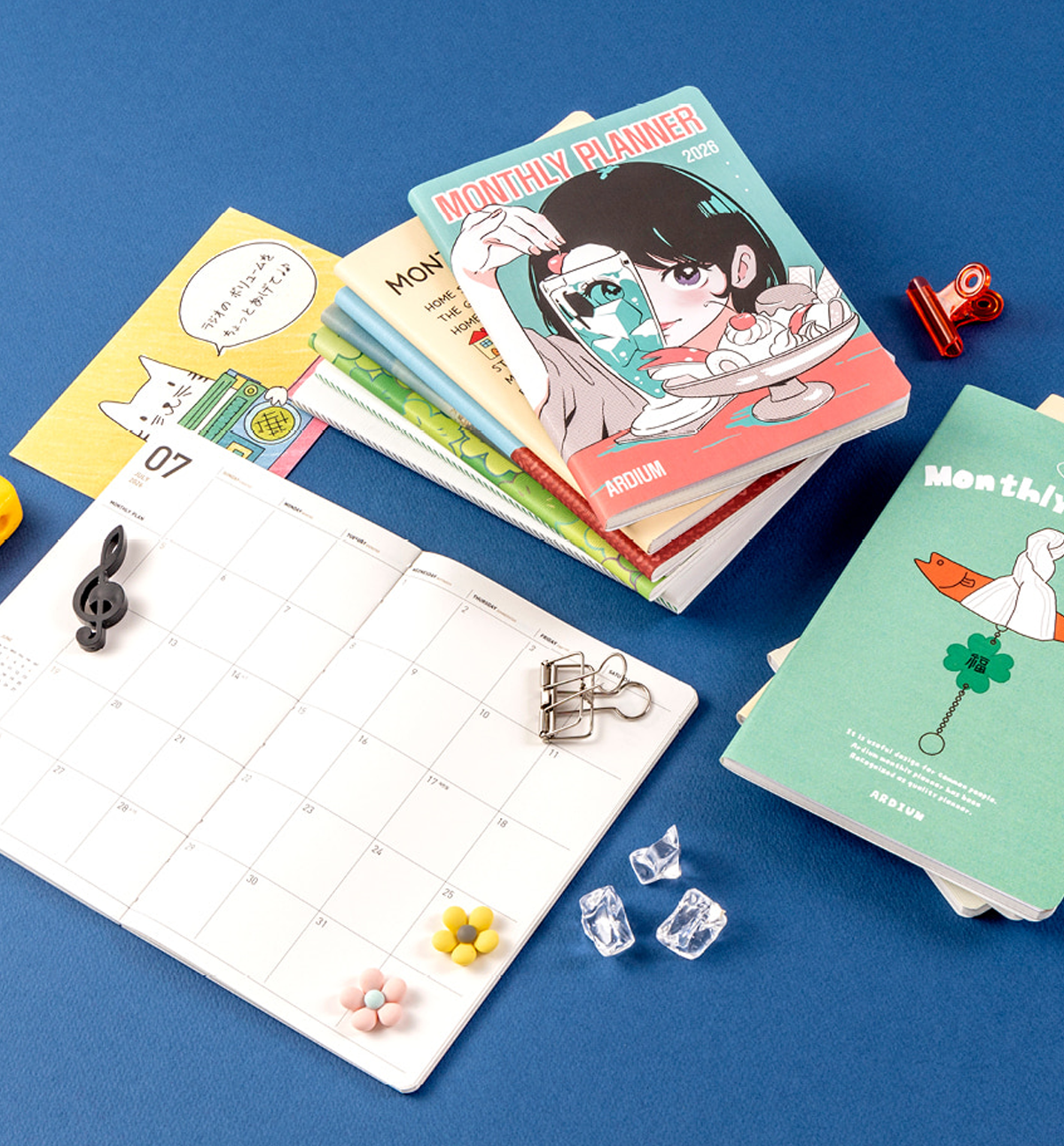 Colorful monthly planners and a grid notebook on a blue background